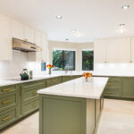 Bright kitchen with sage green island and white countertops