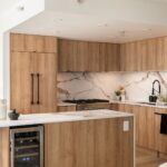Condo kitchen with Calacatta-style veined countertops, a full-height stone backsplash and wood-look cabinets