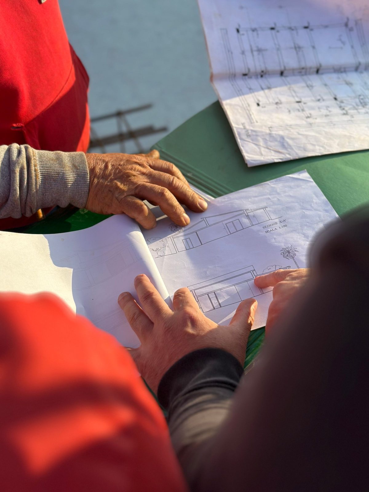 Hands reviewing a printed elevation drawing on a job site