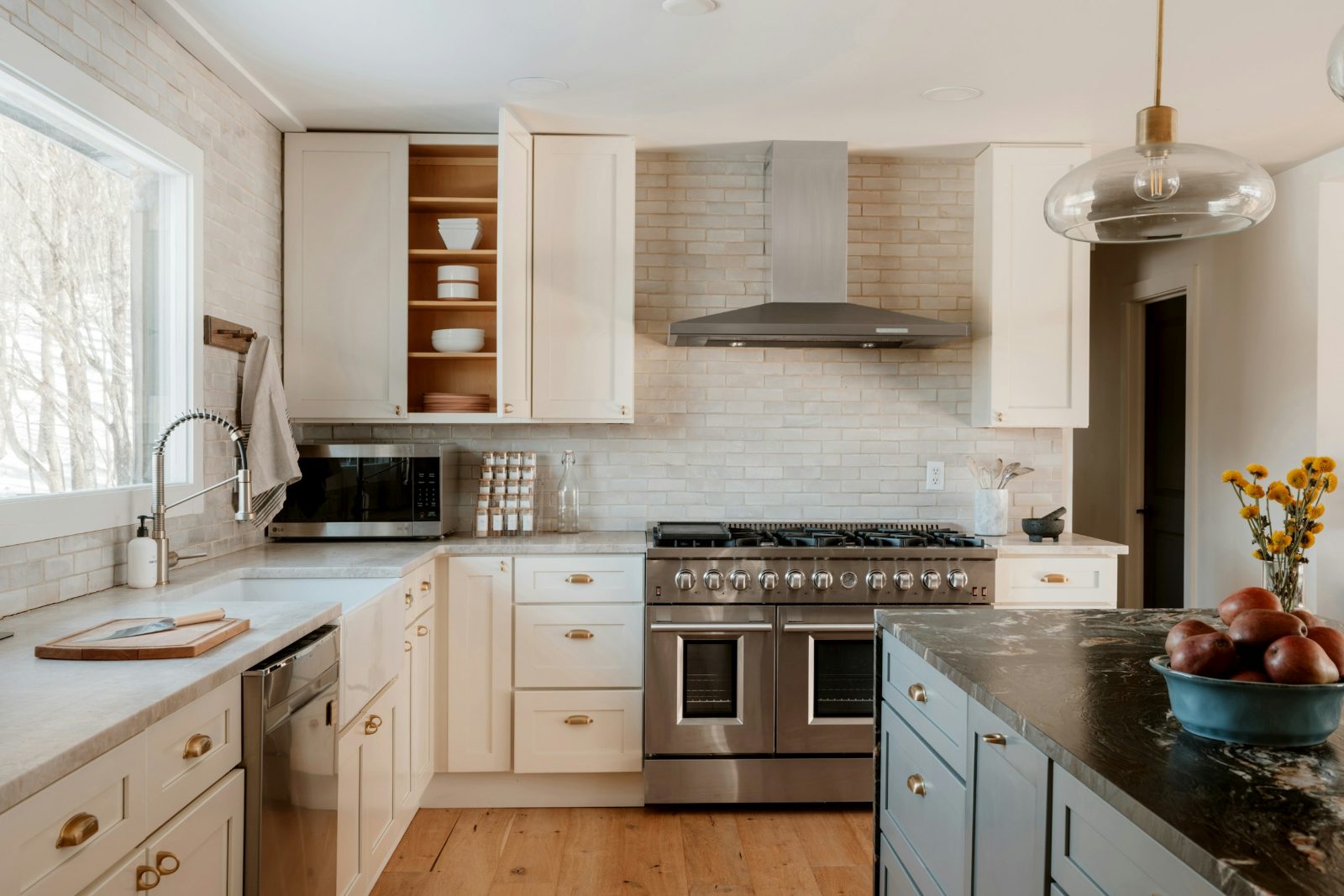White shaker kitchen with a stainless wall hood mounted above a gas range and a tiled backsplash