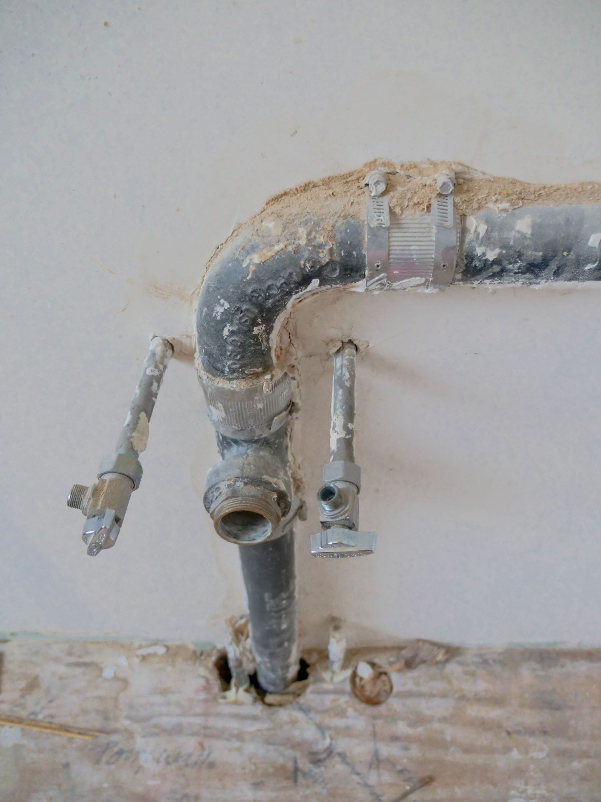 Drain stub and hot and cold supply lines coming through a bathroom wall
