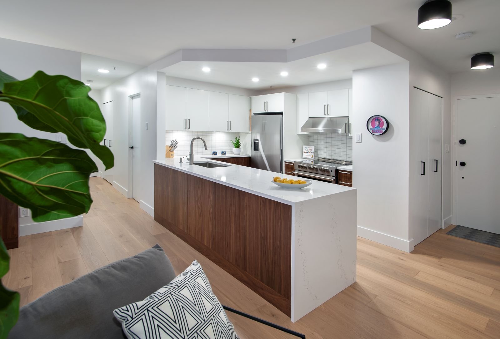 Walnut condo island with a finished panel facing the living room and a white quartz waterfall end