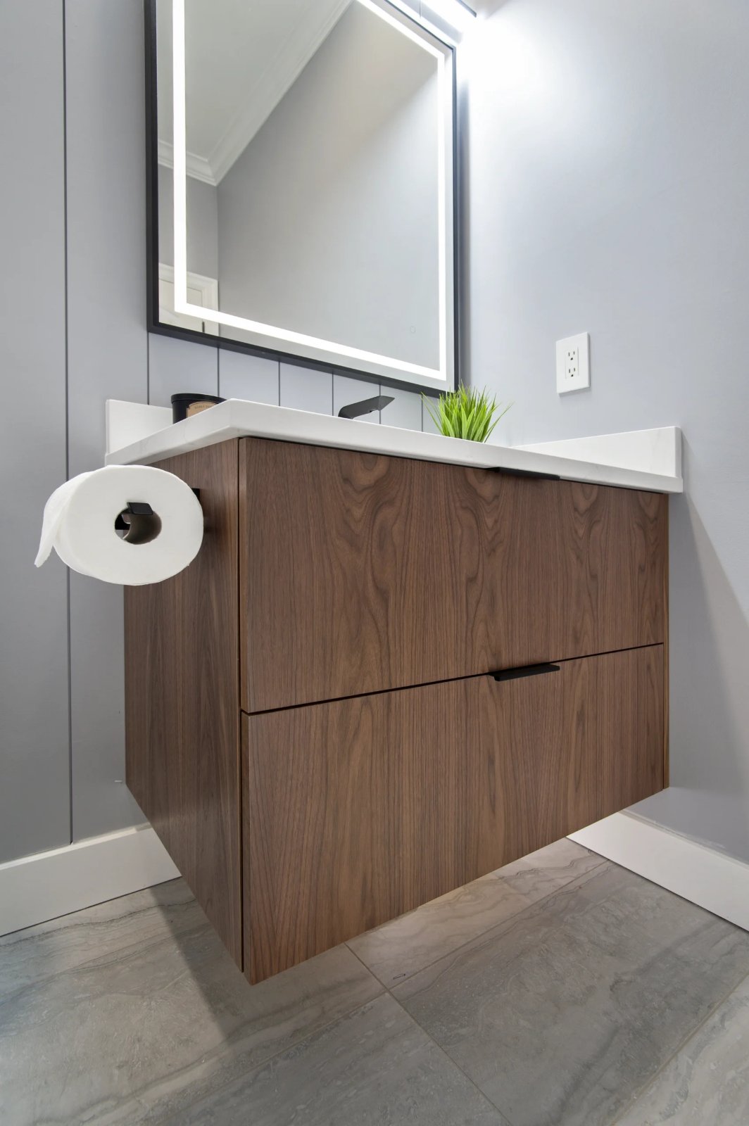 Floating walnut powder room vanity with two drawers, a white quartz top and a lighted mirror